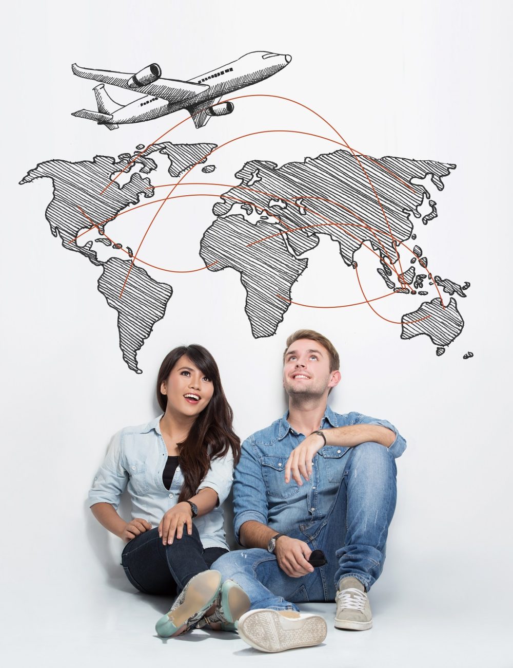 A portrait of happy young mixed race couple sitting on the floor together and imagining to have trip around the world